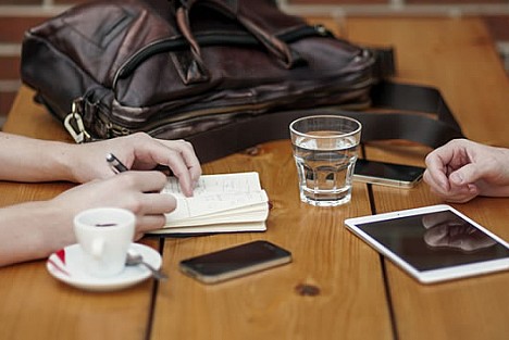 Smartphone and tablet on a table with two pairs of hands