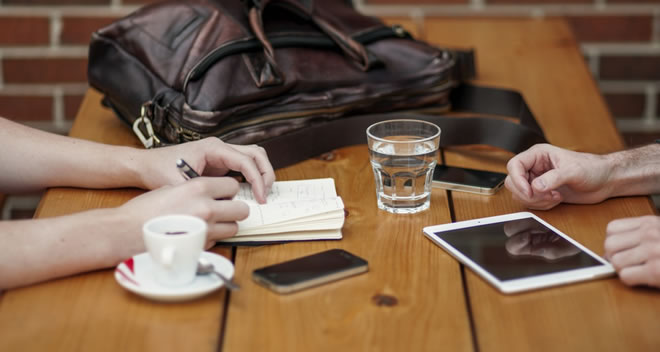 Smartphone and tablet on a table with two pairs of hands